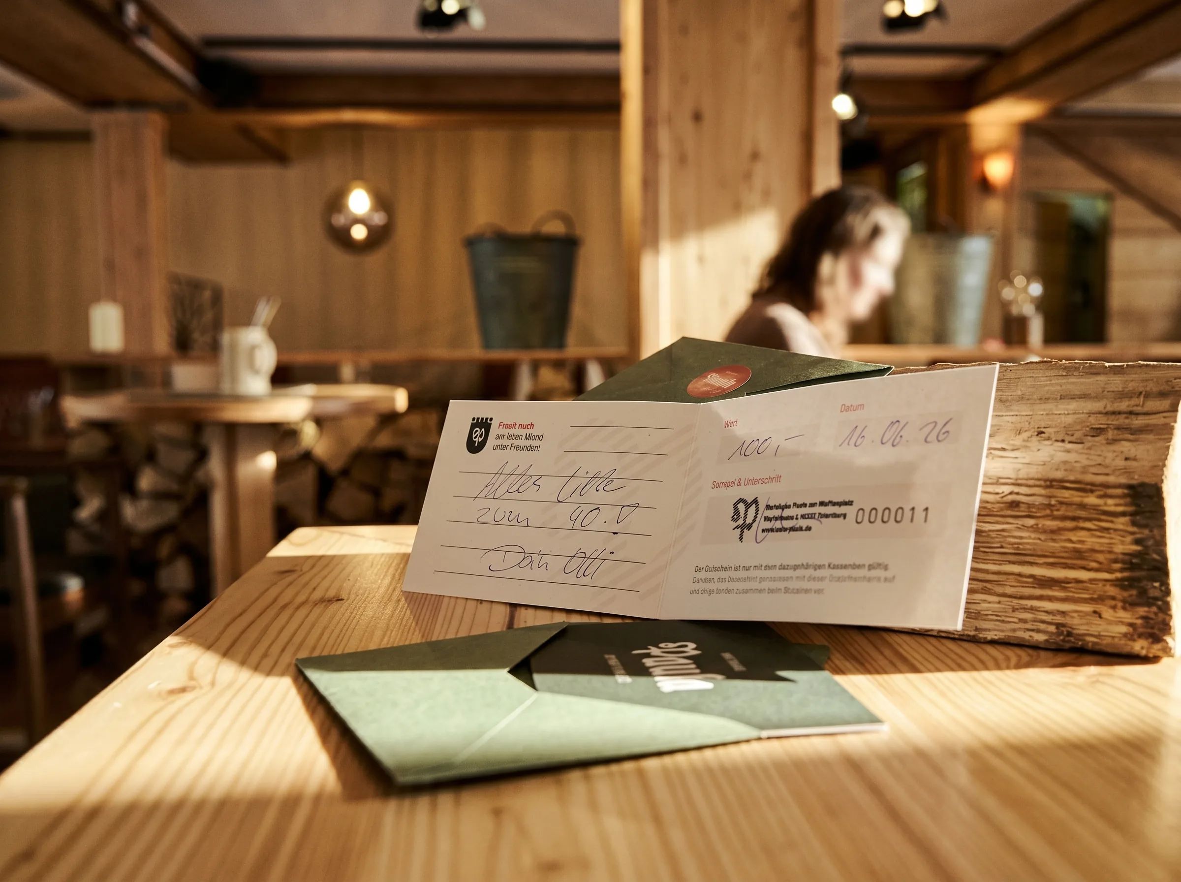 Gutschein vom Wirtshaus Paula auf einem Holztisch im Gastraum